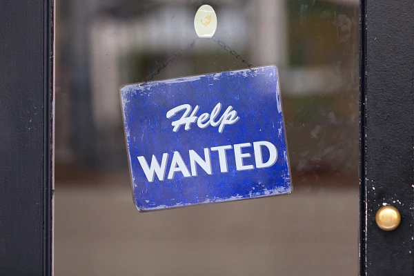 "Help Wanted" sign hanging in door window